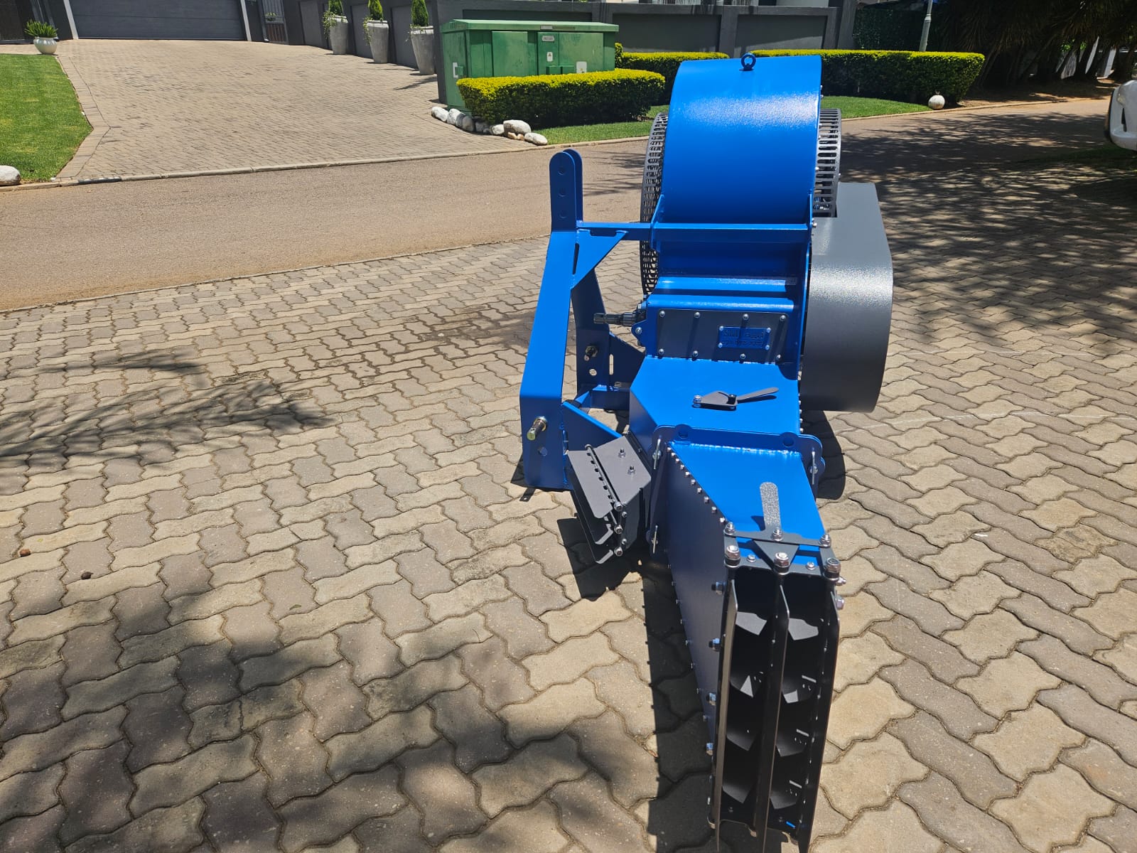 Blue and grey blower implement standing on a paved driveway