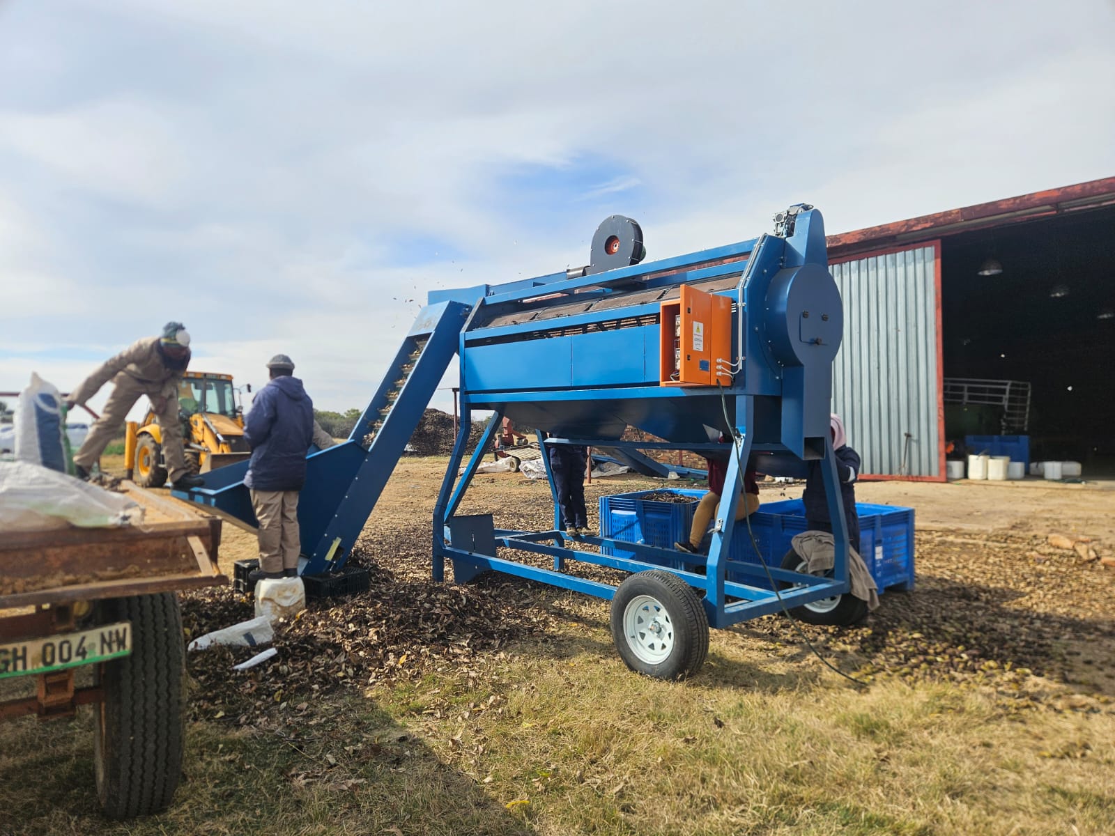 SMJ Harv-Assist machine working in an orchard with harvesters nearby