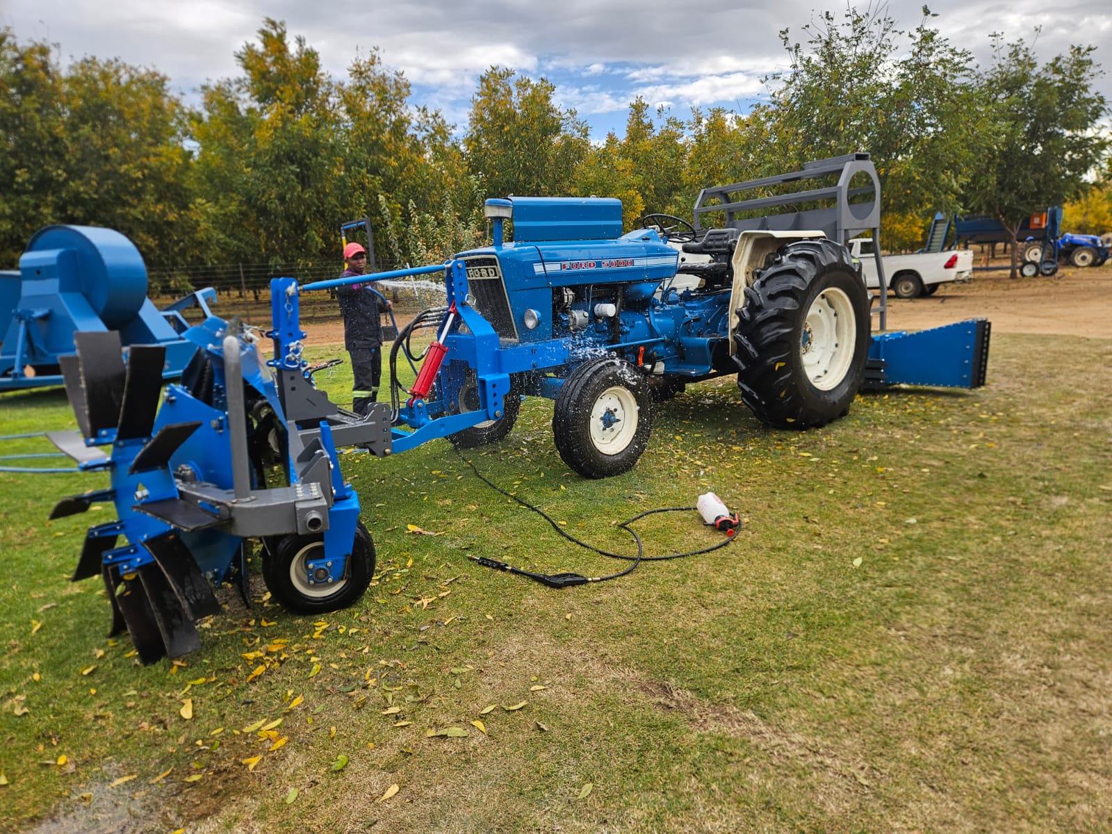 Blue tractor and SMJ orchard equipment being washed down on the lawn